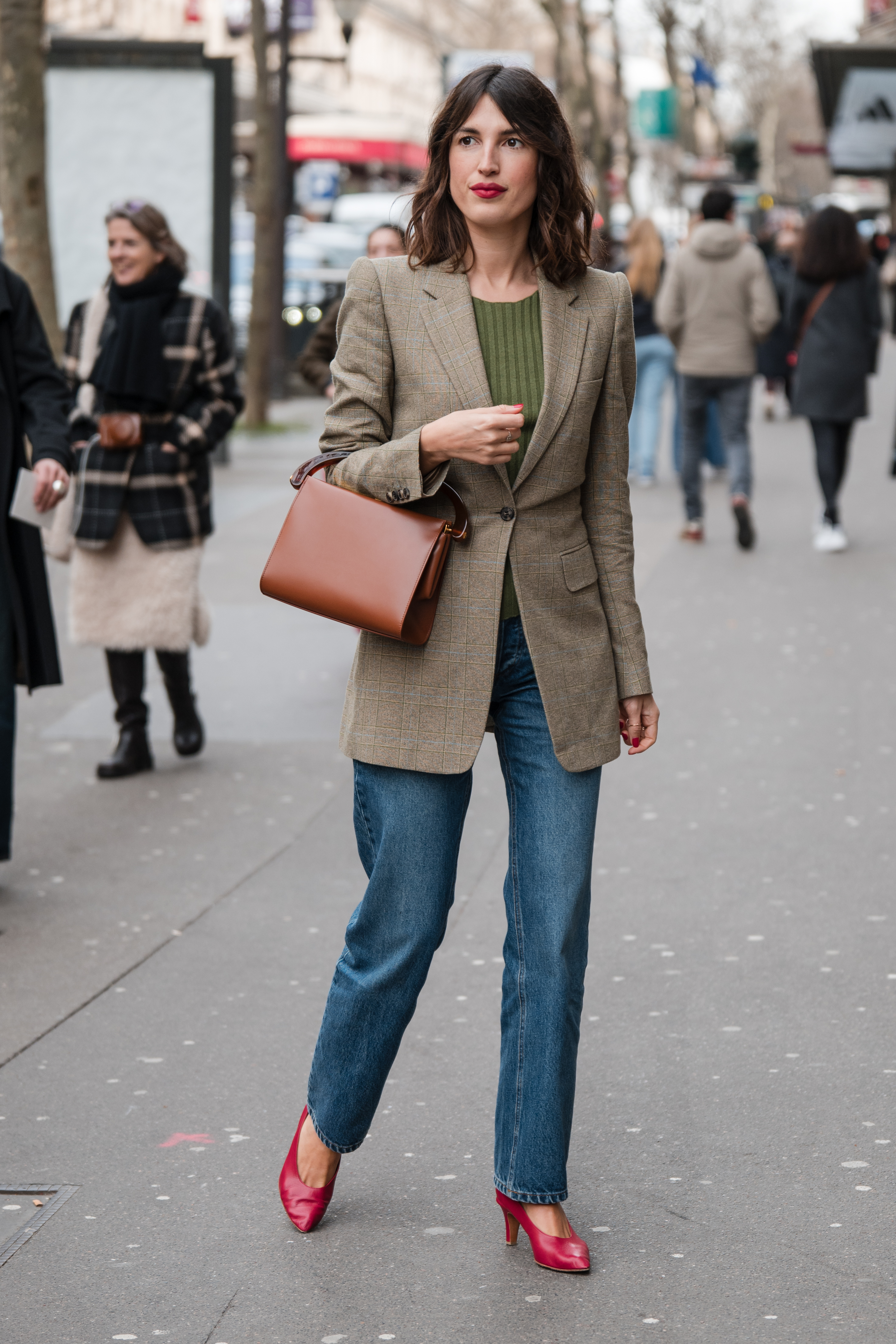 Jeanne Damas i a green top and fitted blazer with jeans and red heels at Paris Fashion Week 2024.