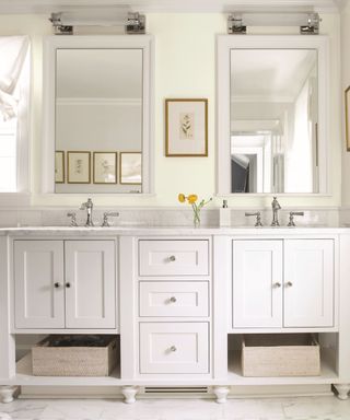 A white farmhouse small bathroom with two rectangular mirrors with lights over them, and two white vanities with silver faucets and cabinets and drawers