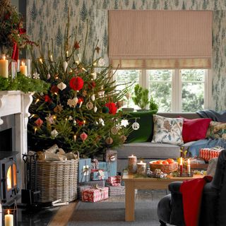 A living room with a botanical wallpaper and a real Christmas tree with paper and wooden decorations