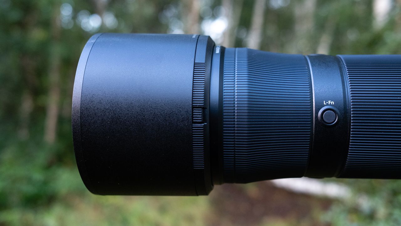 Close up photos of the Nikkor Z 180-600mm f/5.6-6.3 VR mounted on a tripod with foliage in the background