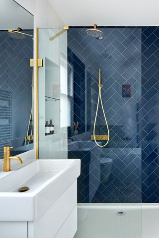 shower room with dark blue metro tiles, white vanity and gold hardware