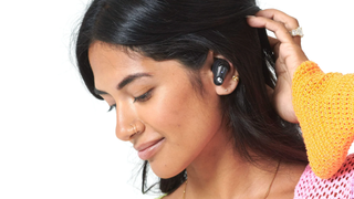A young woman with black hair wearing the Skullcandy Method 540 ANC earbuds in black