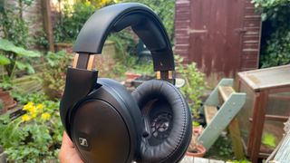 Sennheiser HD 620S headphones held in hand with garden in background