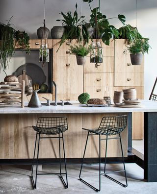 plywood kitchen with quartz/marble countertop, black bar stools, plants