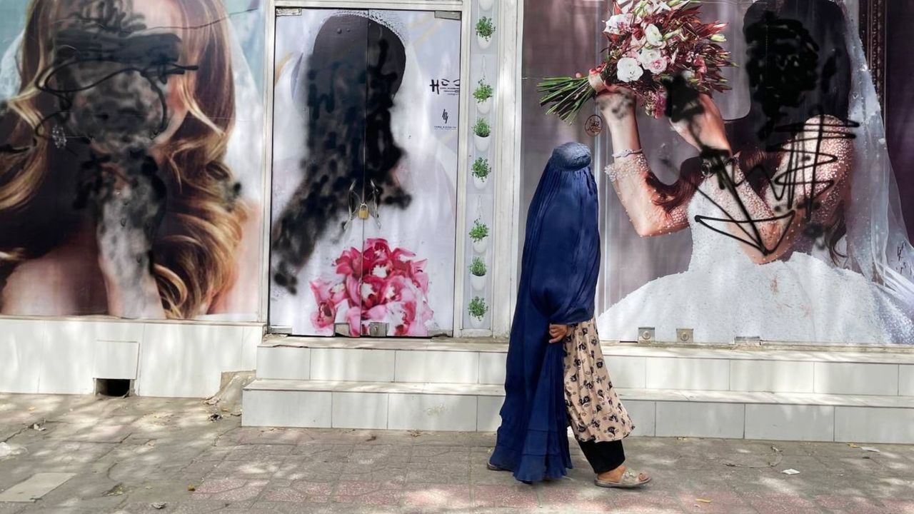 A woman in Afghanistan walks past a closed beauty salon