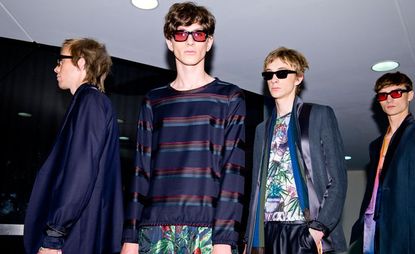 Four models wearing glasses in a dark room
