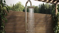 An outdoor shower from Better Bathrooms in front of some wooden panelling in a garden. 