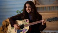 Sade Laflamme Snow holds a guitar as Alice in Season 4 of The Way Home. Her hair is down and she is wearing a dark shirt.