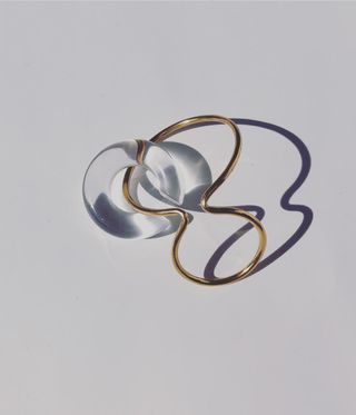 Woman's earring for unpierced ears by Saskia Diez. Ear cuff made of a gold frame and a round clear stone.