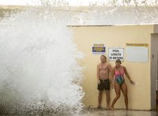 Two swimmers brave hazardous surf conditions at a pool in Sydney, Australia.