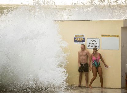 Two swimmers brave hazardous surf conditions at a pool in Sydney, Australia.