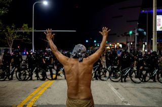 A protester holds up his hands in front of a row of police officers during a rally in response to the recent death of George Floyd an unarmed black man who died while in police custody in Minneapolis in Miami Florida on May 31 2020 Thousands of National Guard troops patrolled major US cities after five consecutive nights of protests over racism and police brutality that boiled over into arson and looting sending shock waves through the country The death Monday of an unarmed black man George Floyd at the hands of police in Minneapolis ignited this latest wave of outrage in the US over law enforcements repeated use of lethal force against African Americans this one like others before captured on cellphone video Photo by Ricardo ARDUENGO AFP Photo by RICARDO ARDUENGOAFP via Getty Images