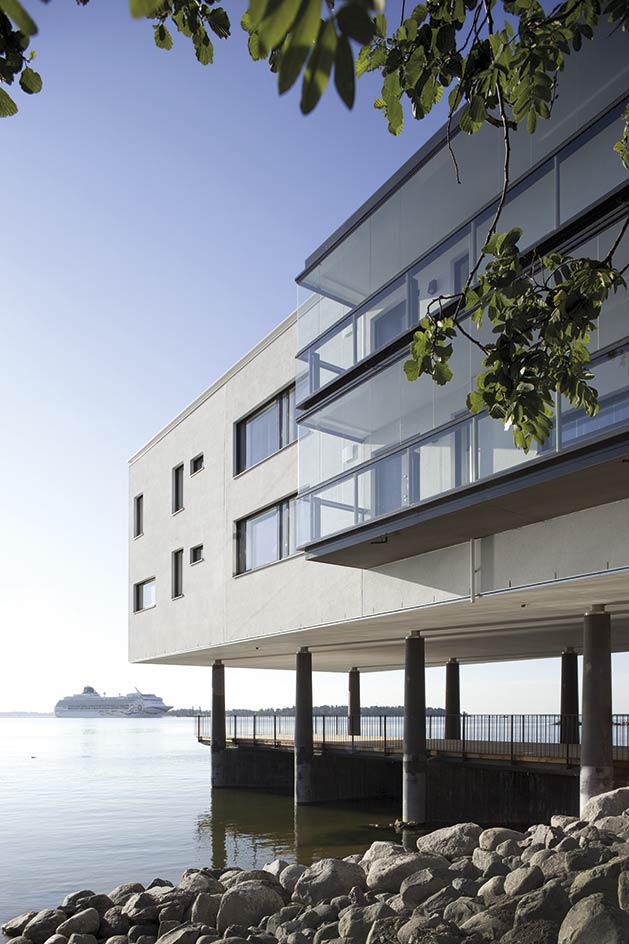 A view of a building outside with water and cruise ship in the distance