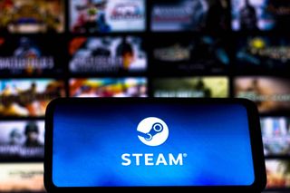 The Steam Logo on a mobile phone in front of a wall of games.