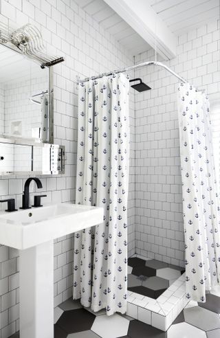 Bathroom with basin and mirror above and shower with curtains and white tile walls and hexagonal tile floor