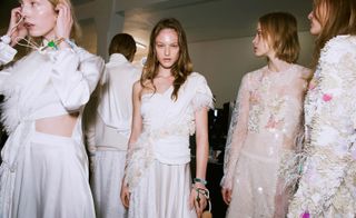 Models wear fill white and pink dresses with embellishments