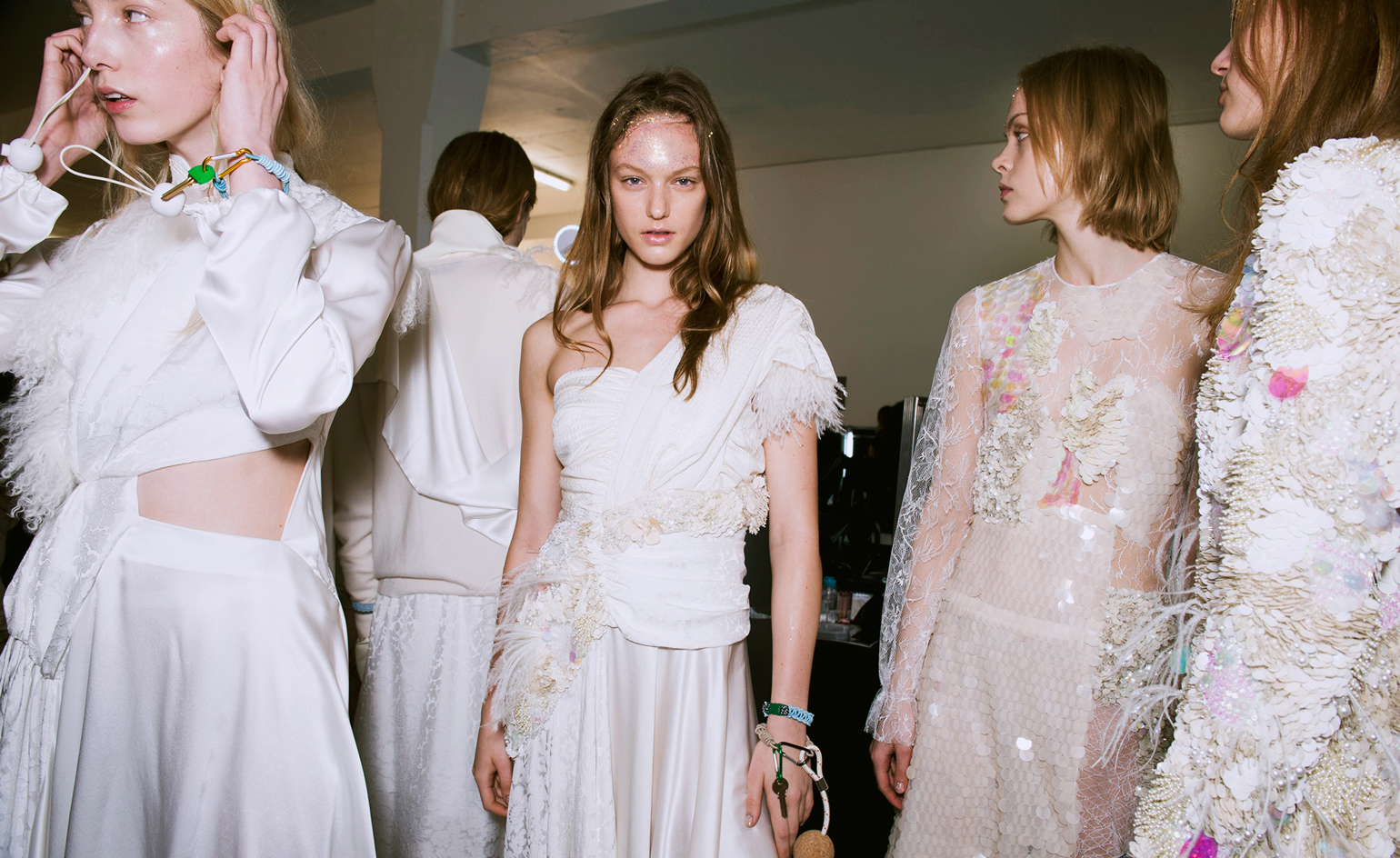 Models wear fill white and pink dresses with embellishments