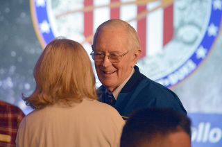 Backdropped by his mission patch, astronaut Charlie Duke chats with guests at a brunch celebrating the 50th anniversary of his Apollo 16 moon landing, April 2, 2022 in Houston.
