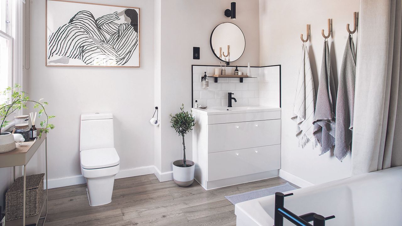 White bathroom with grey towels and wooden flooring