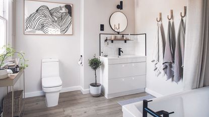 White bathroom with grey towels and wooden flooring