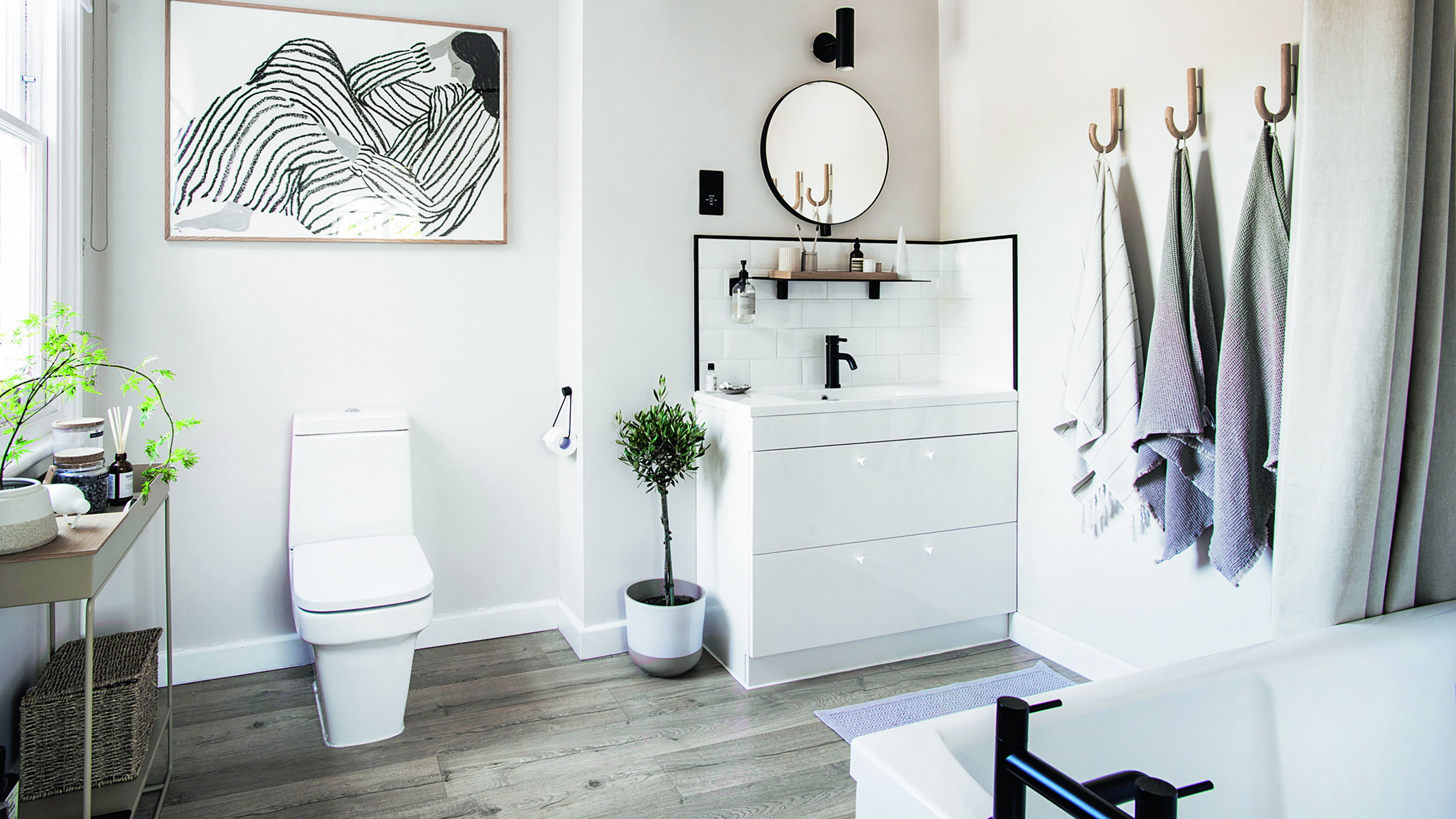 White bathroom with grey towels and wooden flooring