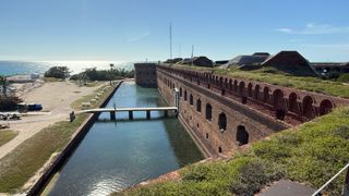 a brick structure next to water under a blue sky.