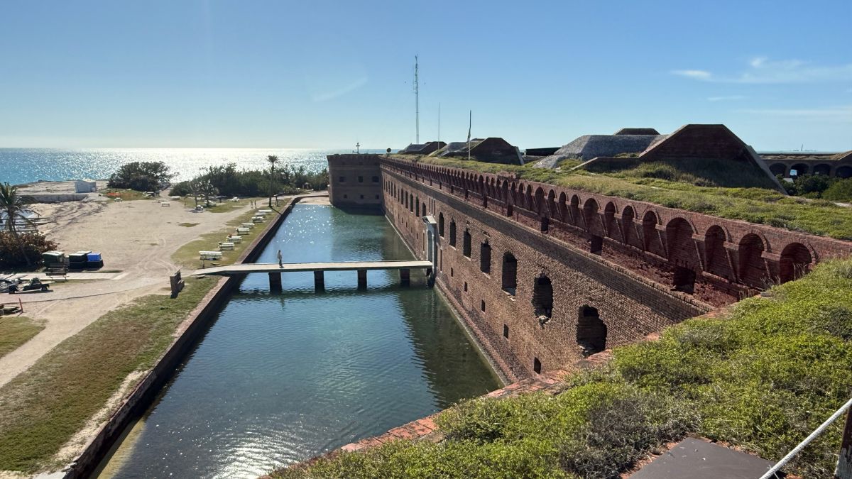 a brick structure next to water under a blue sky.