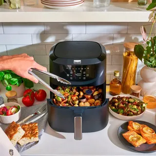 A bella Pro air fryer cooking vegetables on a countertop.