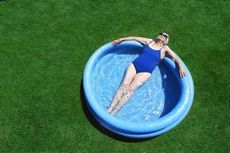 Elderly Woman Lies in a Blue Paddling Pool, Sunbathing and Relaxing