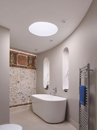 round rooflight in modern bathroom with flint wall
