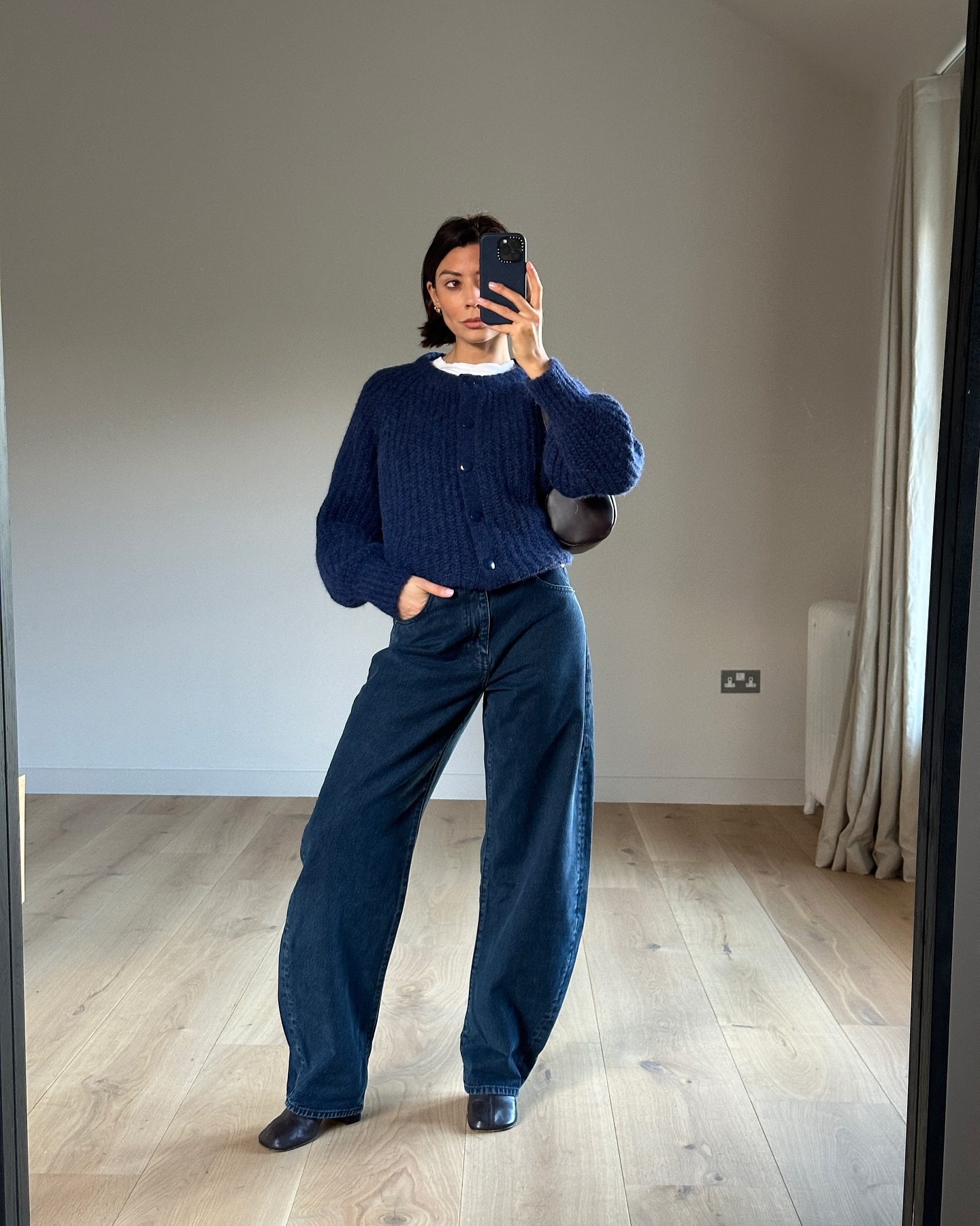 An image of @smythsisters with a navy cardigan, one of the leading colour trends of 2025, with barrel leg jeans and round toe boots.