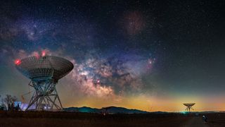 An image of two radio telescope dishes beneath a sky of swirling stars 