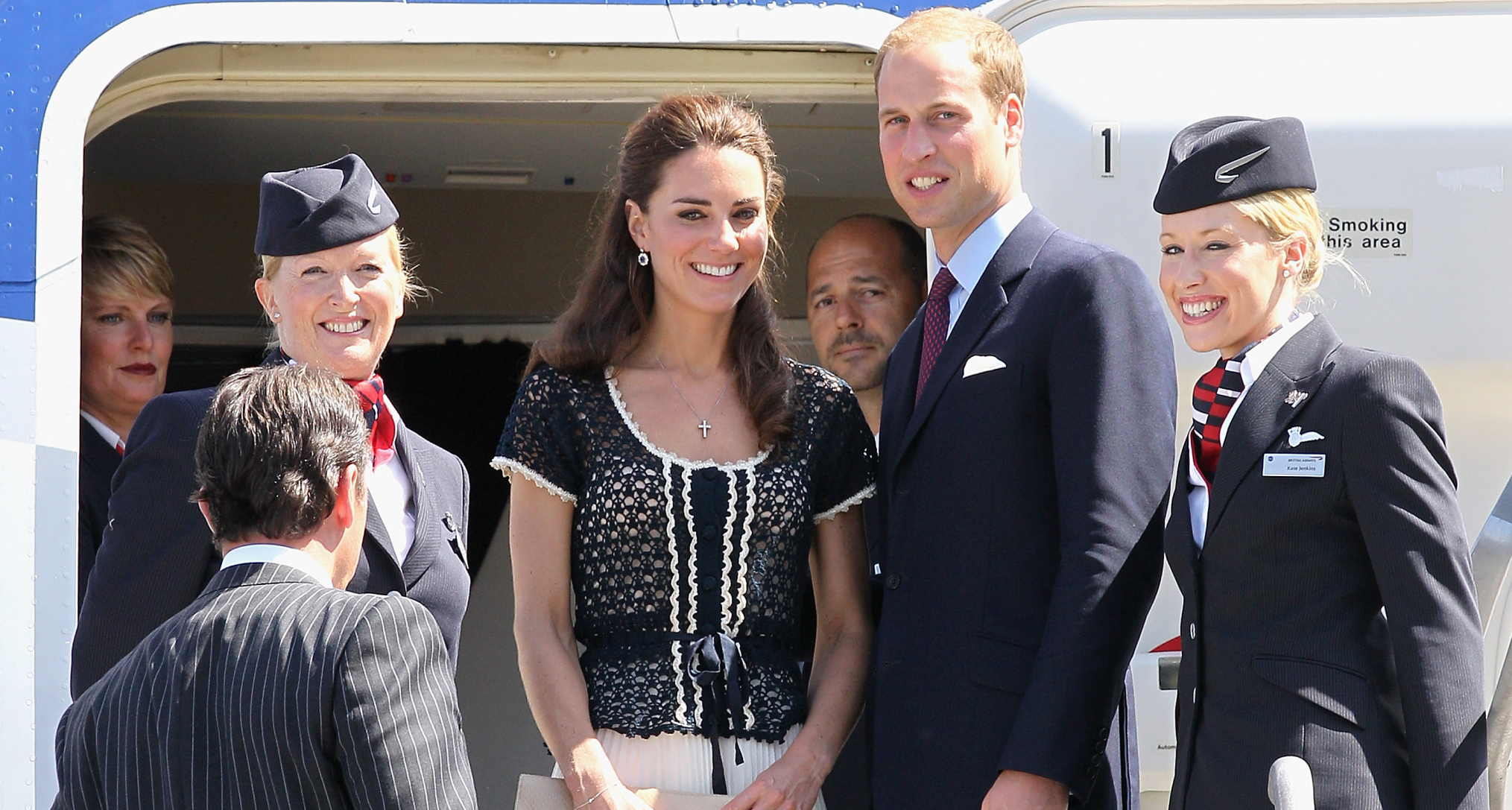 Prince William and Princess Kate standing with flight attendants on a British Airways flight