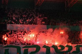Maccabi Haifa fans light red flares during a match against Panathinaikos in October 2023.