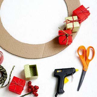 A round piece of carboard and assorted miniature presents with a glue gun and scissors