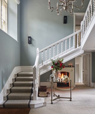 A hallway carpet idea with grey carpet, a darker grey staircase runner, light blue walls and white woodwork