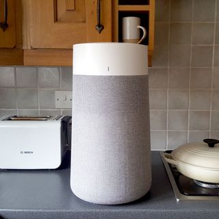 The Blueair Blue Max 3250i Air Purifier with grey fabric cover in a kitchen with grey tiles and worktop
