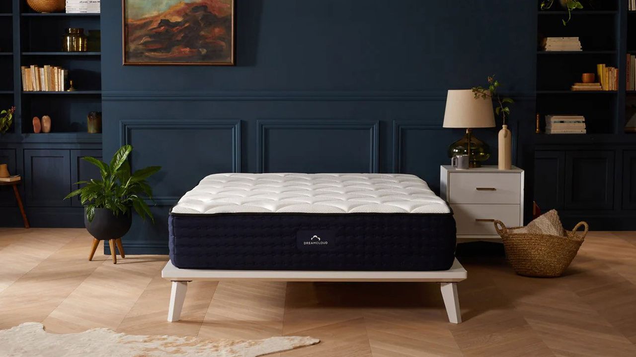 The DreamCloud Luxury Hybrid mattress in a bedroom with dark walls