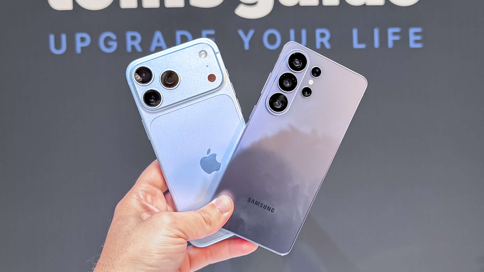 The iPhone 18 Pro Max and Galaxy S26 Ultra in hand in front of a Tom's Guide logo