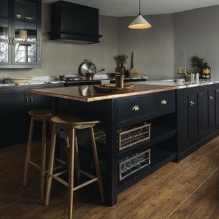 black kitchen island with aged copper and marble tops