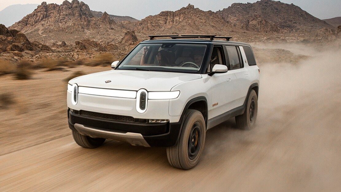 white rivian r1s driving through the desert