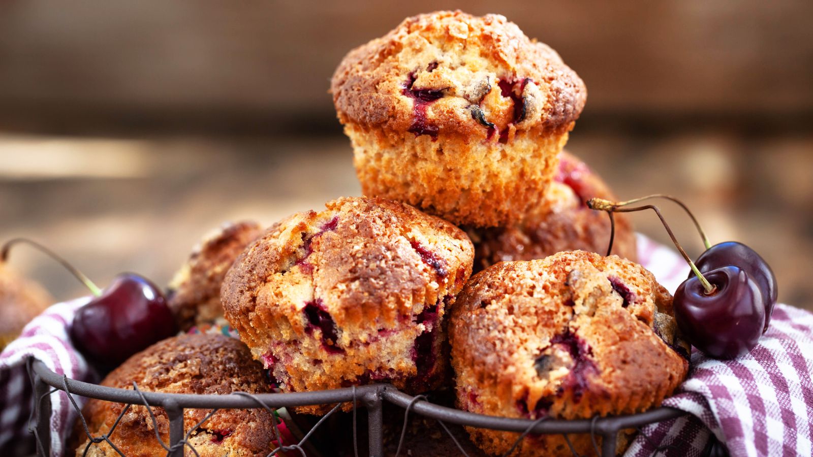 Cherry muffins in a basket with check napkin and fresh cherries