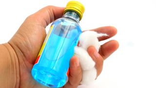 Rubbing alcohol and cotton balls held in a hand