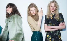 Models wearing attire from the Topshop Unique A/W 2015 collection. Faux fur coats in pastel green, an elegant beige blouse, and a black dress embroidered with wild dandelion stems.