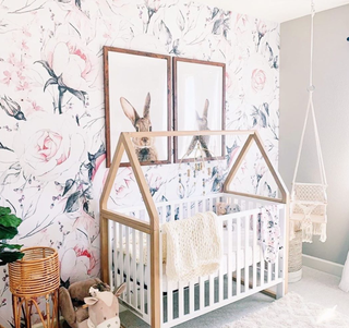 Girls' nursery ideas, with floral wallpaper, wooden furniture and macrame hanging.