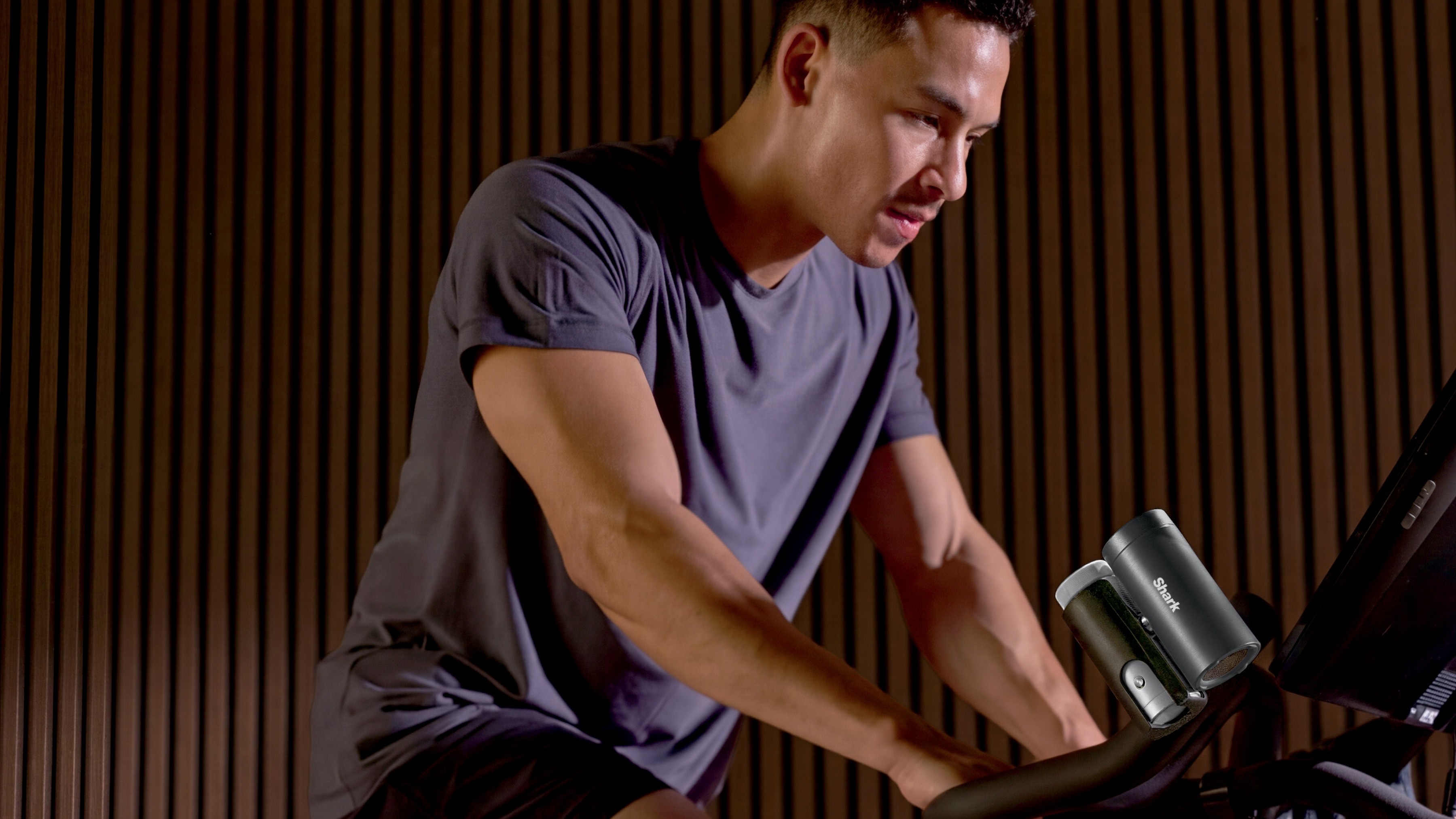 رجل يستخدم دراجة تمرين مع مروحة رذاذ شخصية من Shark ChillPill متصلة بالمقود