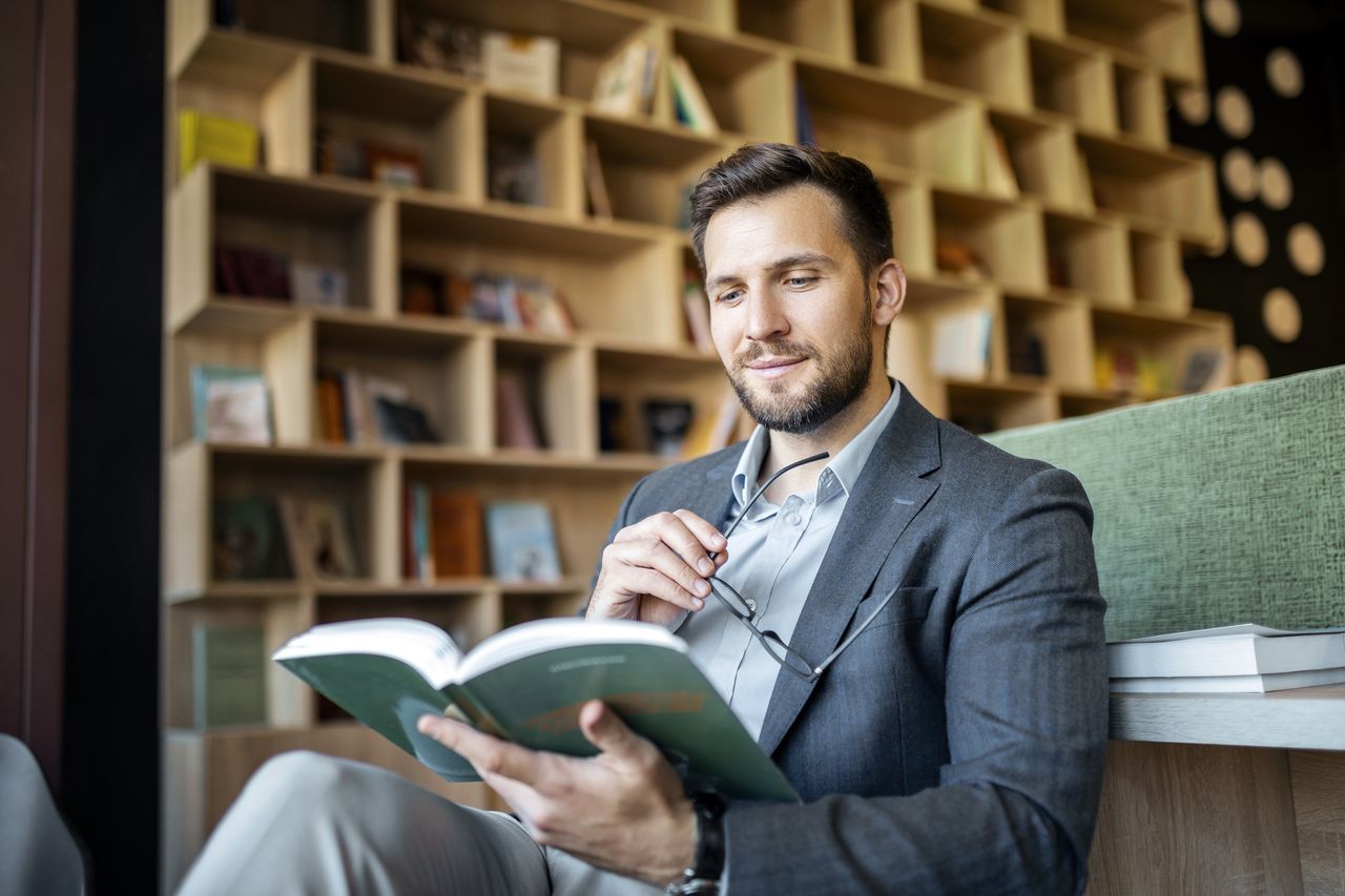 Smiling businessman reading a book