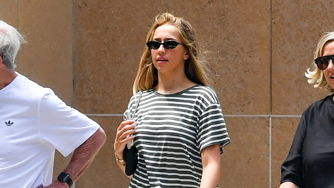 Tate McRae wearing a striped T-shirt, light-wash jeans, and wedge-heel flip-flops