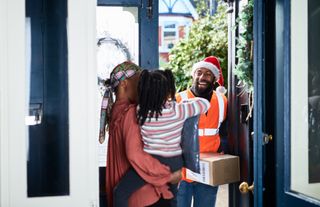 man with beard wearing Santa hat delivering parcel to woman with daughter, anticipation, convenience, service occupation