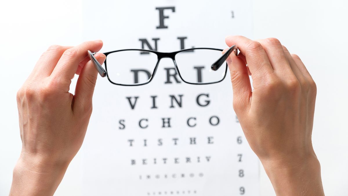 How often should you get an eye exam? An image of a person holding black-framed glasses in front of eye exam letters